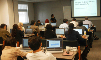 a group of people sitting in a classroom with laptops