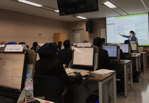 a classroom with people sitting at desks and computers