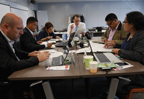 a group of people sitting at a table with laptops