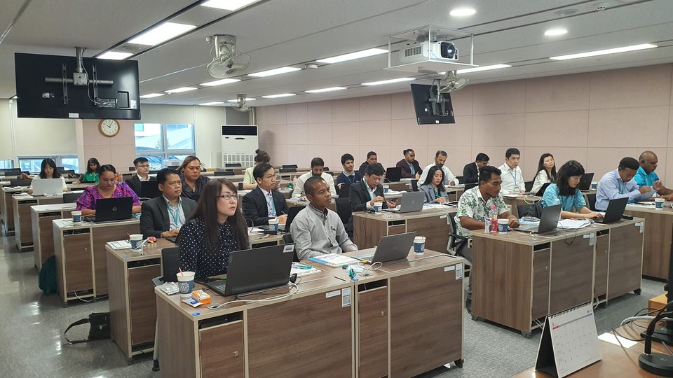 a group of people sitting at desks in a classroom